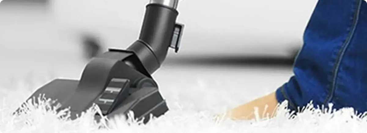 Close-up of a professional vacuuming a white carpet in Belle Chasse.