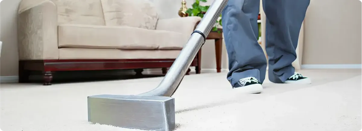 Carpet cleaning technician using a hot-water extraction wand on a light-colored carpet in a living room, New Orleans, LA.